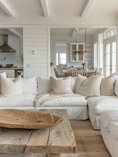 a living room filled with white furniture and lots of pillows on top of it's couches