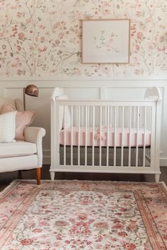 a baby's room with floral wallpaper and a white crib