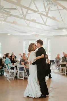 a bride and groom share their first dance at the wedding reception in front of an audience