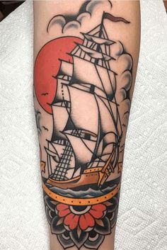 a tattoo with a ship on it and clouds in the sky behind it, as well as an orange sun