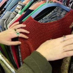 a woman's hand reaching for a ring on top of a rack of clothes