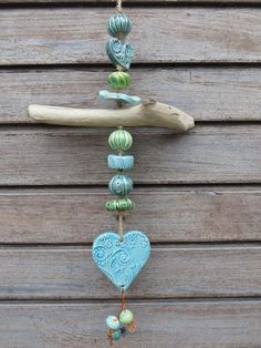 a blue heart hanging from a tree branch with beads and other items attached to it