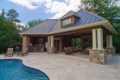 a pool house with a covered patio and hot tub next to it's swimming pool