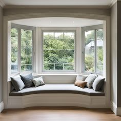 a window seat in the corner of a room with pillows on it's sides