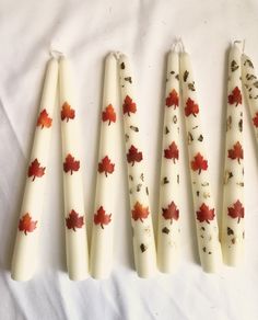 five white candles with red maple leaves on them