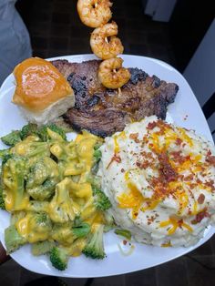 a white plate topped with meat and veggies next to macaroni and cheese