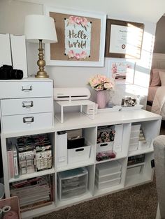 a white desk with lots of drawers and some pictures on the wall in front of it