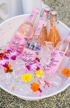 a bucket filled with lots of bottles of pink wine and flowers on top of it