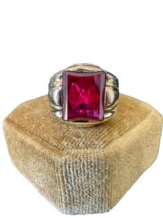 Handsome vintage 10k yellow gold 1940s era ring featuring a vibrant created ruby! The deep red gem weighs an estimated 6 carats, is emerald cut, and securely bezel set. The substantial setting is detailed with a decorative design on the shoulders. Charming vintage piece of fine jewelry for him or her, featuring July's birthstone! ERA - Circa 1940 METAL / MATERIAL - 10k yellow gold, 1 created ruby (estimated 6 carats) [Synthetic ruby contains essentially the same chemical composition & properties as its natural counterpart, but is created by man in controlled setting.] HALLMARKS / HISTORY - 10k SIZE / MEASUREMENTS - Size: 10, Created Ruby: Approx. 12 x 10 mm, Back of shank: 4.5 mm, Ring Head Height: 16 mm, Weight: 6.9 grams Classic Ruby Ring With Polished Finish For Collectors, Classic Red Signet Ring Stamped 14k, Collectible Red Ruby Ring In 14k Gold, Vintage Ruby Rings With Polished Finish, Antique Ruby Rings With Polished Finish, Vintage Red Hallmarked Signet Ring, Collectible Ruby Ring With Polished Finish, Antique Hallmarked Ruby Signet Ring, Antique Red Rectangular Rings