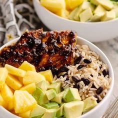 two bowls filled with rice, fruit and meat next to each other on a table