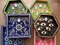 three decorative boxes with eyes and flowers painted on them