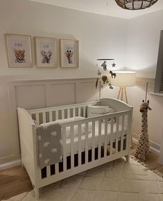 a baby's room with a crib, lamp and pictures on the wall