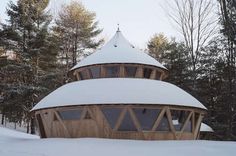 a wooden structure in the snow surrounded by trees