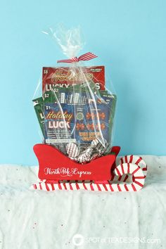 a red and white basket filled with candy on top of a bed