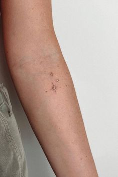 a person's arm with a small star tattoo on the left side of their arm