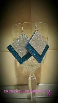 a pair of earrings sitting on top of a wine glass in front of a wall