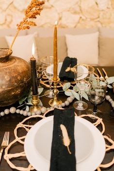 the table is set with candles, plates and napkins