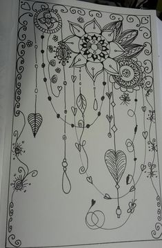 an open book with black and white drawings on the pages, including flowers and beads