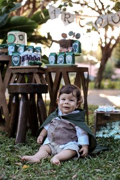 a little boy sitting on the ground in front of some wooden stools and tables