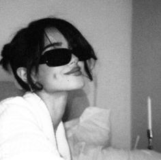 black and white photograph of a woman with sunglasses on her face looking up at the camera