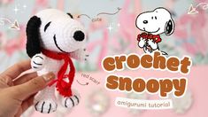 a hand holding a small crochet snoopy dog with a red scarf around it's neck