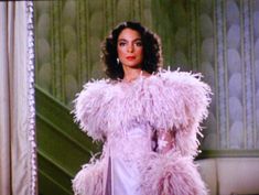 a woman in a pink dress and feathered coat