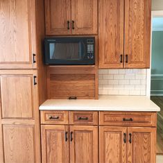 a kitchen with wooden cabinets and a black microwave on the wall above the stove top