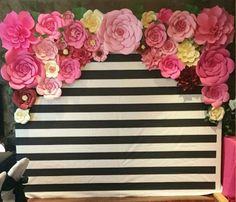 there is a wall decorated with paper flowers and black and white striped walls behind it