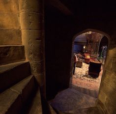 an archway leading to a living room in a stone walled building with stairs and rugs on the floor