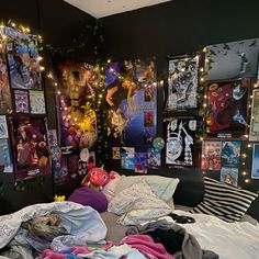 an unmade bed with posters on the wall and lights strung from it's sides