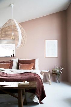 a bed sitting in a bedroom next to a wooden table and lamp hanging from the ceiling