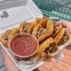 a person holding a container with some food in it and dipping sauce on the side