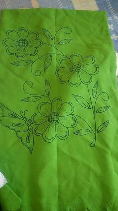 a green bag with flowers on it sitting on a table top next to a piece of cloth