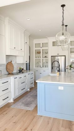 a kitchen with white cabinets and light blue island in front of the countertop area