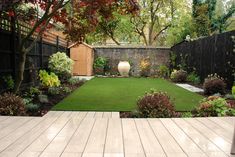 a backyard garden with grass and wooden decking