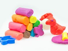 a pile of colorful play dough sitting on top of a white table next to toys