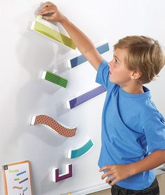 a young boy standing next to a white board with magnets on it