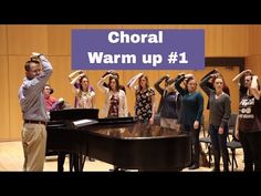 a group of young people standing around a piano in front of a wall with the words choral warm up 1