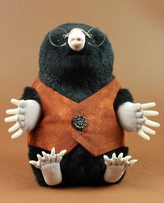 a black and brown stuffed animal with glasses on it's head wearing a vest