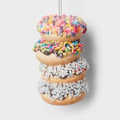 a stack of donuts with sprinkles hanging from a string on a wall