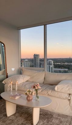 a living room filled with furniture and a large window next to a white couch covered in pillows