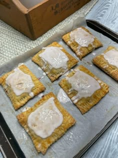 six pastries on a baking sheet with icing in the middle, sitting on a table