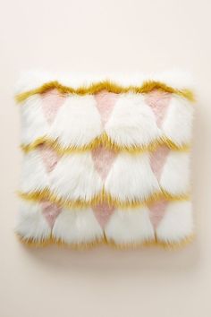 a pink and white fur pillow on top of a beige wall with an orange stripe