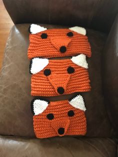 two crocheted foxes sitting on top of a brown chair