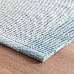 a close up view of a rug on a wooden floor with light blue and white colors