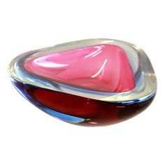 a pink and red glass object sitting on top of a white surface with no one around it