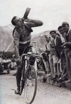 a man riding on the back of a bike while holding a baseball bat over his head