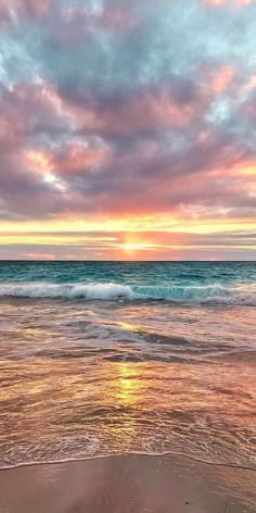 the sun is setting over the ocean with waves coming in from the water and sand