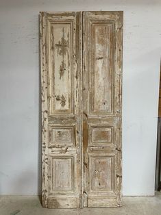 an old pair of wooden doors sitting on top of a cement floor in front of a white wall