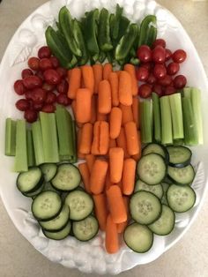 a white plate topped with cucumbers, carrots and other veggies